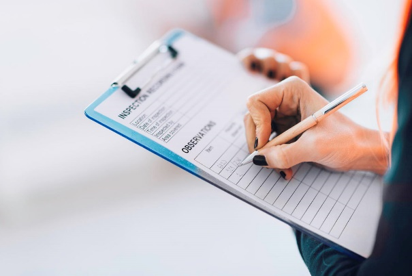 Image of someone writing on a clipboard