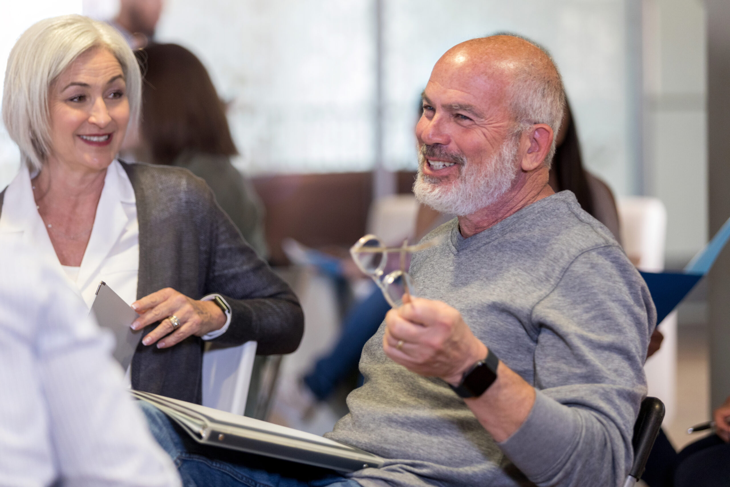 Smiling mature man discusses something with neighbors during homeowner association meeting.