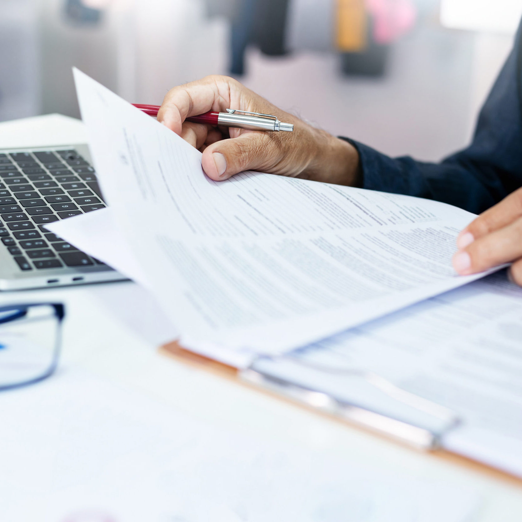 Asian businessman reviewing document reports at office workplace with computer laptop. legal expert, professional lawyer reading and checking financial documents or insurance contract